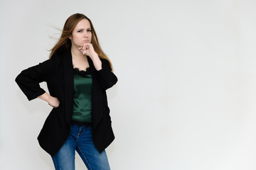 Concept portrait above the knee of a pretty girl, a young woman with long beautiful brown hair and a black jacket and blue jeans on a white background. In studio in different poses showing emotions.