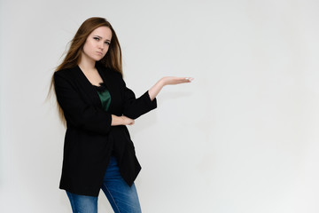 Concept portrait above the knee of a pretty girl, a young woman with long beautiful brown hair and a black jacket and blue jeans on a white background. In studio in different poses showing emotions.