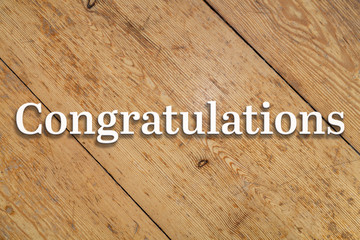 'Congratulations' white text on a wooden background. 
