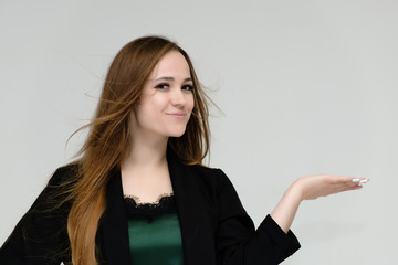 Fototapeta premium Concept close-up portrait of a pretty girl, a young woman with long beautiful brown hair and a black jacket on a white background. In the studio in different poses showing emotions.