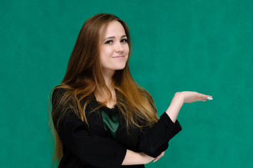 Concept close-up portrait of a pretty girl, a young woman with long beautiful brown hair and in a black jacket on a green background. In the studio in different poses showing emotions.