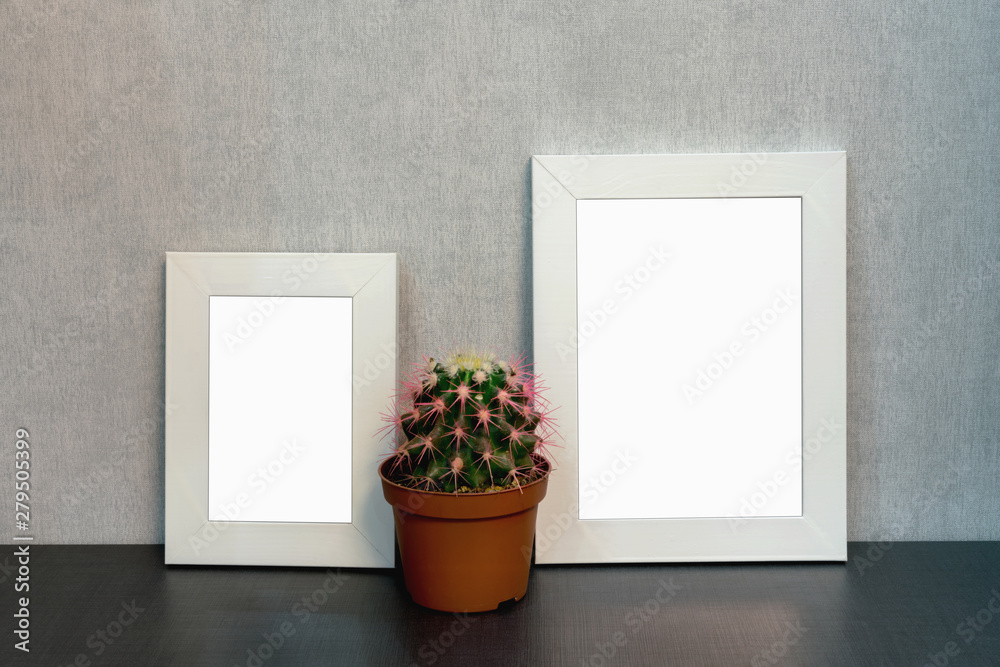 Wall mural two white wooden photo frames are on the shelf in the interior of the room at home, a pot of cactus 