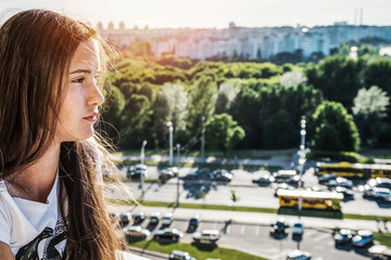 Fototapeta na wymiar profile portrait of young girl with long hair, cityscape background