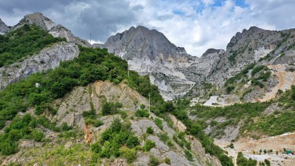 Fototapeta na wymiar Aerial view of mountain of stone and marble quarries in the regional natural park of the Apuan Alps located in the Apennines in Tuscany, Massa Carrara Italy. Open pit mine