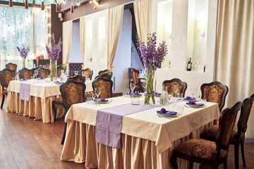 Table setting with white plates, wineglasses, cutlery and flowers,  on table, copy space. Place setting at wedding reception. Table served for wedding banquet in restaurant