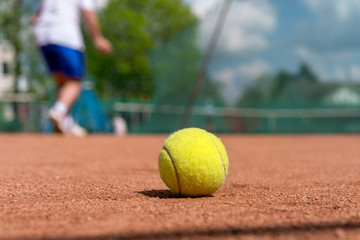 yellow tennis ball on clay court during training session at tennis academy