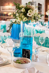 Beautiful floral arrangement and candles in glass vases on wedding table in restaurant, copy space. Luxury wedding decorations. Table setting