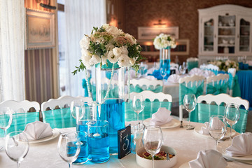 Luxury table setting with cutlery, wineglasses and floral arrangement on table, copy space. Place setting at wedding reception. Table served for wedding banquet in restaurant