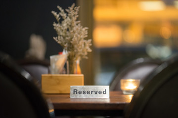Table in vintage or bistro restaurant is already reserved for customer. Objects on table are...