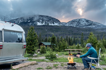 A camper warming his hands at the campfire, Timber Creek Campground, Rocky Mountain National Park - obrazy, fototapety, plakaty