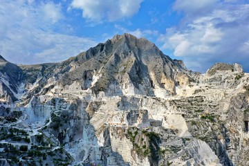 Fototapeta na wymiar Aerial view of mountain of stone and marble quarries in the regional natural park of the Apuan Alps located in the Apennines in Tuscany, Massa Carrara Italy. Open pit mine