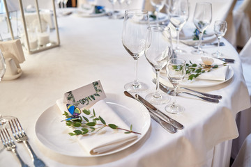 Table setting with blank guest card on empty white plate and cutlery on table, copy space. Menu mockup, place setting at wedding reception. Table served for wedding banquet in restauran