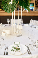 Table setting with cutlery, wineglasses and flower decorations on table, copy space. Place setting at wedding reception. Table served for wedding banquet in restauran