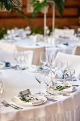 Table setting with blank guest card on empty white plate and cutlery on table, copy space. Menu mockup, place setting at wedding reception. Table served for wedding banquet in restauran