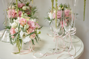 Luxury floral arrangement of pink and white flowers in glass vases and decorated wineglasses on wood table, copy space. Wedding decorations, holiday concept