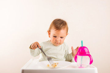 Baby toddler eating pancakes with fork. Isolated. Copy space