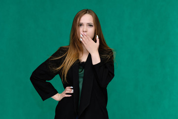 Concept portrait for a belt of a pretty girl, young woman with beautiful brown hair and in a black jacket and green T-shirt on a green background. In the studio in different poses showing emotions.