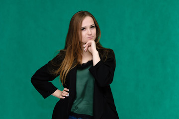 Concept portrait for a belt of a pretty girl, young woman with beautiful brown hair and in a black jacket and green T-shirt on a green background. In the studio in different poses showing emotions.