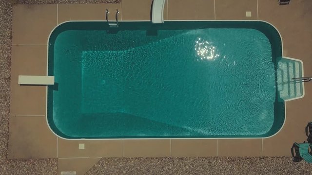 Top down view of an in ground pool with sparkling clear water on a hot day