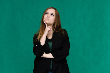 Concept portrait for a belt of a pretty girl, young woman with beautiful brown hair and in a black jacket and green T-shirt on a green background. In the studio in different poses showing emotions.