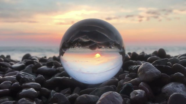 Loop cinemagraph crystal ball on the beach stones sunset, wonderful landscape
