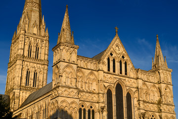 Fototapeta na wymiar Great West Front facade of Salisbury Cathedral with statuary of Saints and Angels and Spire in gold evening light in Salisbury England