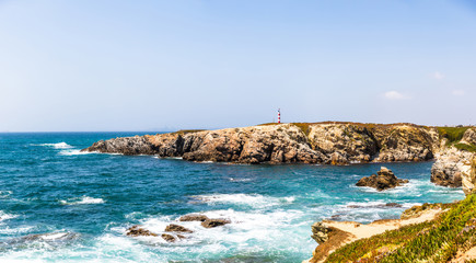 View of the cliffs and the lighthouse near praia pequena beach in Porto Covo, Portugal