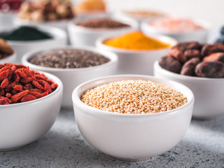Quinoa grain in small white bowl and other superfoods on background. Selective focus. Different superfoods ingredients. Concept and illustration for superfood and detox food