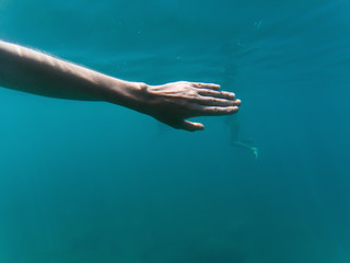 Obraz na płótnie Canvas hand underwater swimming in blue water