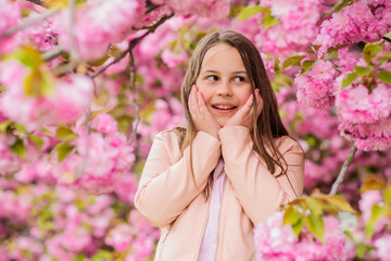 Allergy remedy. Sniffing flowers. Girl enjoying floral aroma. Pollen allergy concept. Kid enjoy cherry blossom sakura. Kid on pink flowers sakura tree background. Child enjoy life without allergy