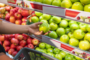 Females hand picking green apple at fruit store
