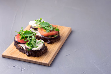 Bruschetta with Grilled Eggplant Tomatoes Cottage Cheese and Fresh Aromatic Herbs on a Wooden Tray Delicious Mediterranean Appetizer Dish Gray Background