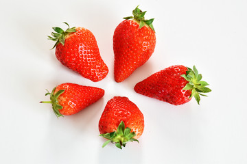 top view of four strawberries on white plane