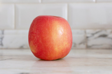 red ripe apple on white kitchen marble table