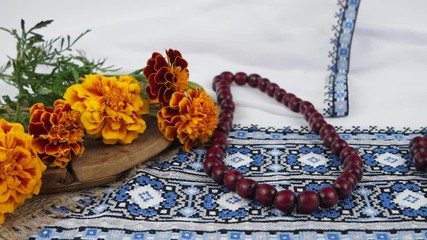 Marigolds and wooden beads on the background of white embroidered fabric - Powered by Adobe