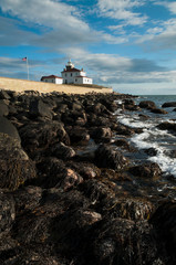 Fototapeta na wymiar Coastal Seaweed Covers Rocks by Watch Hill Lighthouse in Rhode Island