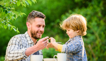 Feeding son natural foods. Stage of development. Feed son solids. Dad and boy eat and feed each other outdoors. Ways to develop healthy eating habits. Feed your baby. Natural nutrition concept