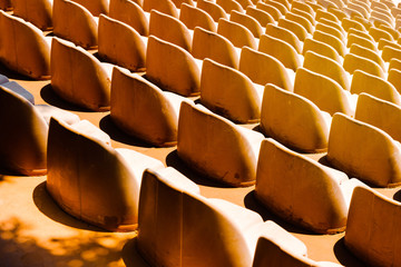 Fototapeta na wymiar Old beige plastic empty seats in the summer theater in the summer sunny day. Chairs are waiting for the audience to a concert in the open.