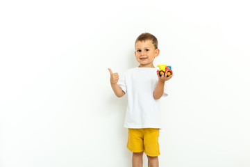 Portrait of a little boy laughing with thumbs up sign on gray background