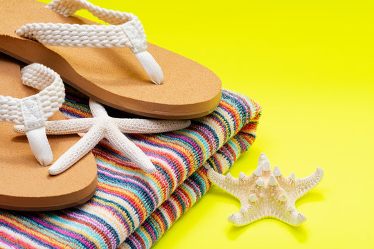 Women's Causal Braided natural color Beach Flip Flops and Colorful Striped Beach Towels decorated with White Finger Starfish on yellow background.
