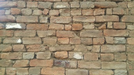 A background of a weathered old exterior brick wall in the sunshine.