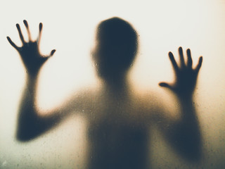 Horror man behind the matte glass in black and white. Blurry hand and body figure abstraction. Halloween background. Murder concept. Criminal concpet.