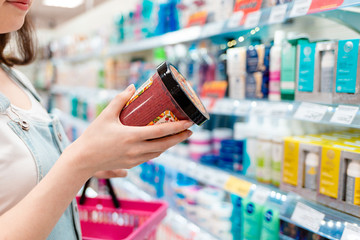 Shopping. The woman is holding a body cream. A jar of cream and hands close-up