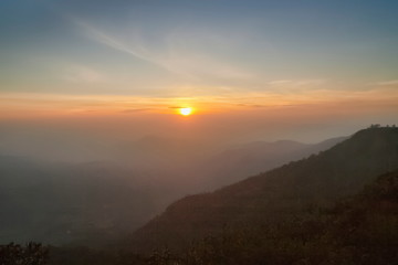 Mountain view morning of top hill around with soft fog and yellow sun light in the sky background, sunrise at top of Phu Ruea National Park, Phu Ruea District, Loei Province, Thailand.