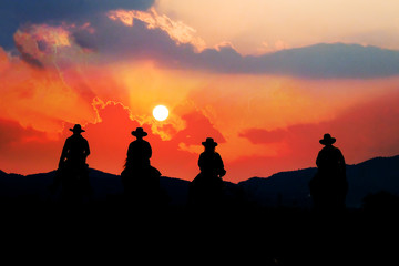 Cowboy on horseback with views of the mountains and the sunset sky.