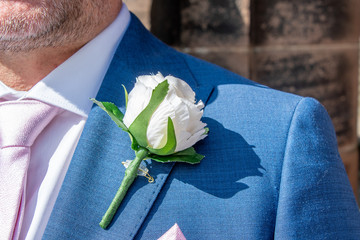 view of a groom wearing an artificial rose buttonhole