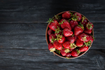 Ripe strawberries are lying on a wooden table on a platter. Submitted by close-up.