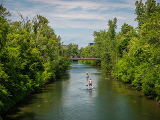 Fototapeta na wymiar Man and woman paddleboarding on a canal in Montreal, Quebec