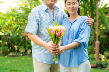 Obraz premium Middle aged couple hold flower together ingreen park