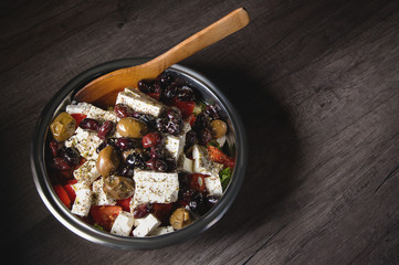Close-up of delicious gourmet tomato and olives feta cheese salad sprinkled with herbs spices in a metal bowl. The concept of delicious and healthy vegetarian food and body detoxification